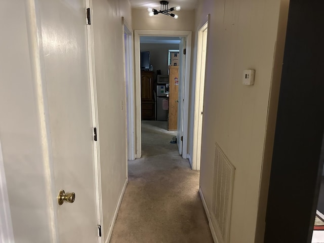 hall with light carpet and a notable chandelier