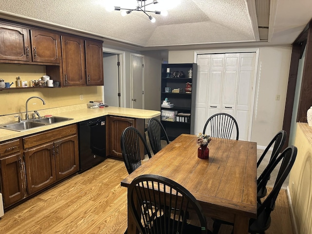 kitchen with kitchen peninsula, sink, an inviting chandelier, black dishwasher, and light wood-type flooring