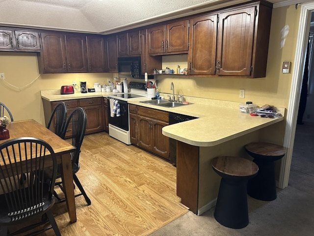 kitchen featuring a textured ceiling, black appliances, sink, light wood-type flooring, and dark brown cabinets