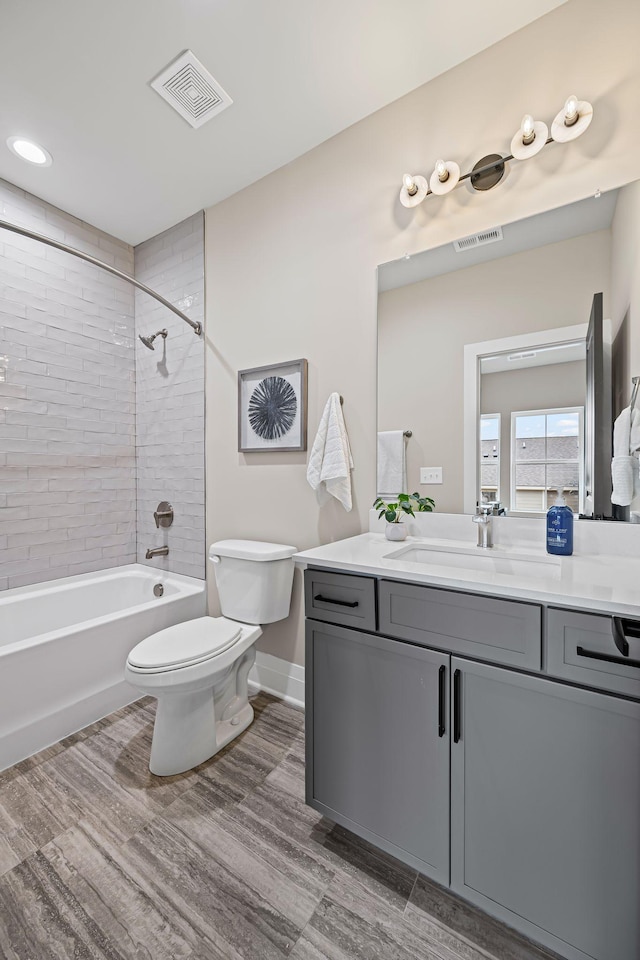 full bathroom with hardwood / wood-style flooring, tiled shower / bath, vanity, and toilet