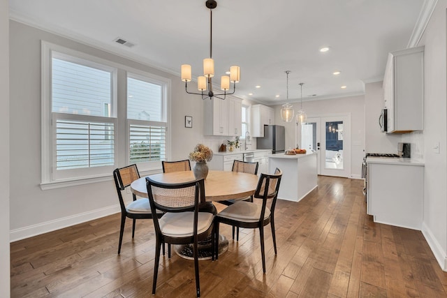 dining space with crown molding, dark hardwood / wood-style floors, and a chandelier