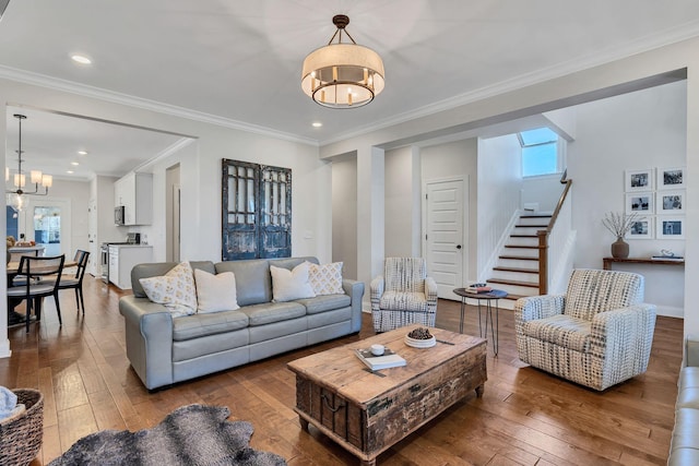 living room featuring wood-type flooring, a healthy amount of sunlight, a notable chandelier, and ornamental molding