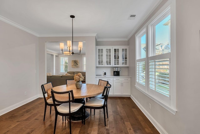 dining area featuring dark hardwood / wood-style flooring, crown molding, and an inviting chandelier