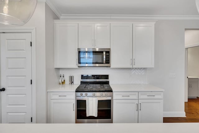 kitchen featuring ornamental molding, appliances with stainless steel finishes, decorative backsplash, and white cabinets