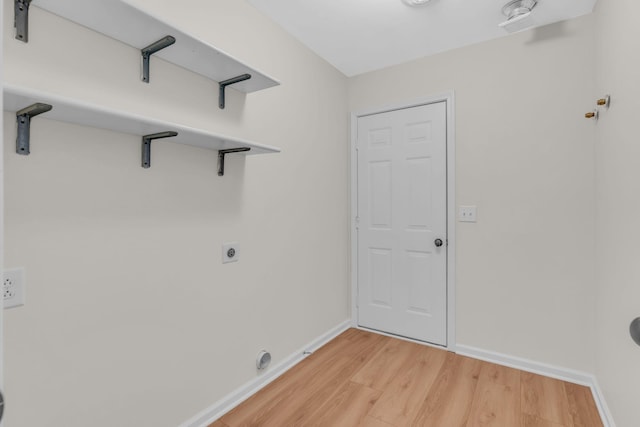 laundry room featuring electric dryer hookup and light hardwood / wood-style flooring