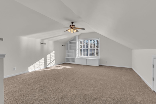 additional living space with light carpet, built in shelves, lofted ceiling, and ceiling fan