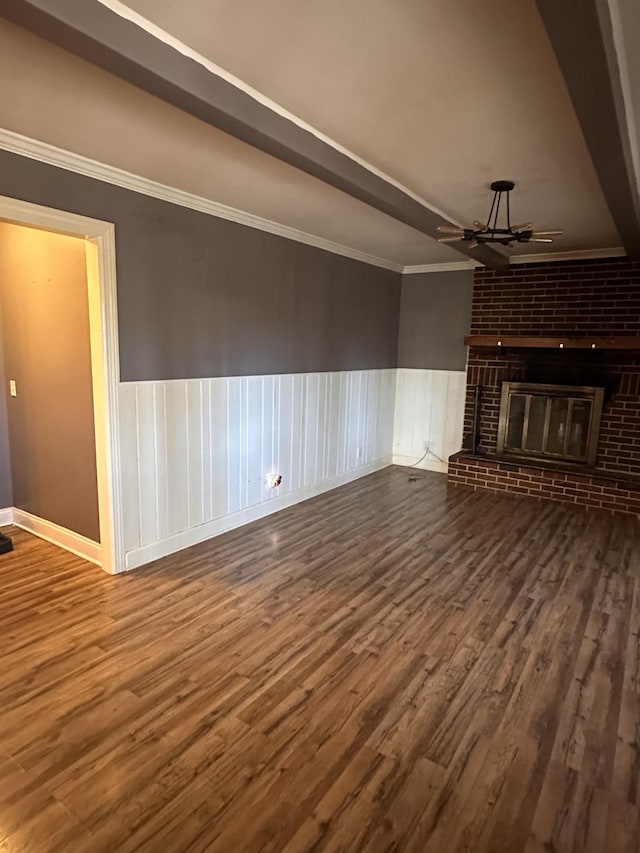 unfurnished living room with ceiling fan, dark wood-type flooring, crown molding, and a fireplace