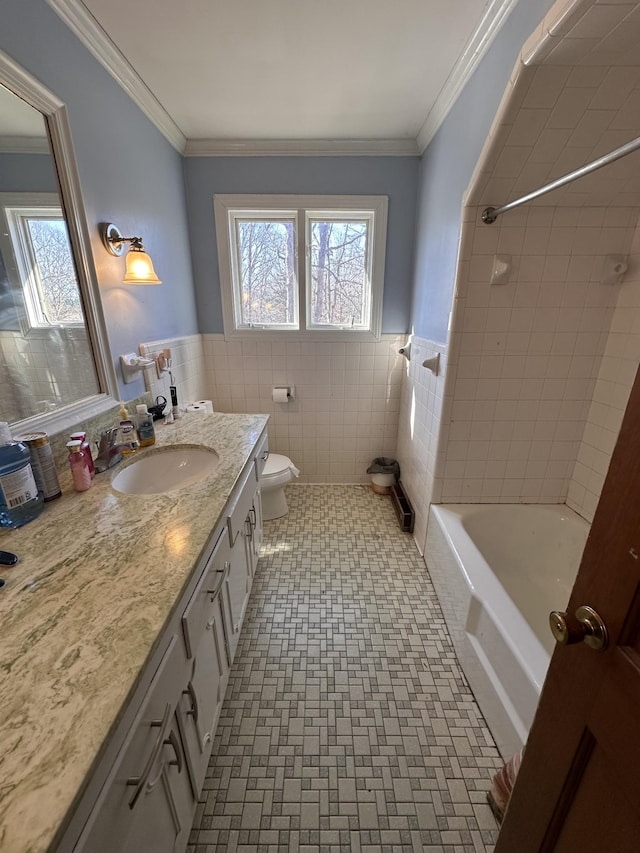 full bathroom featuring toilet, tiled shower / bath, tile walls, crown molding, and vanity