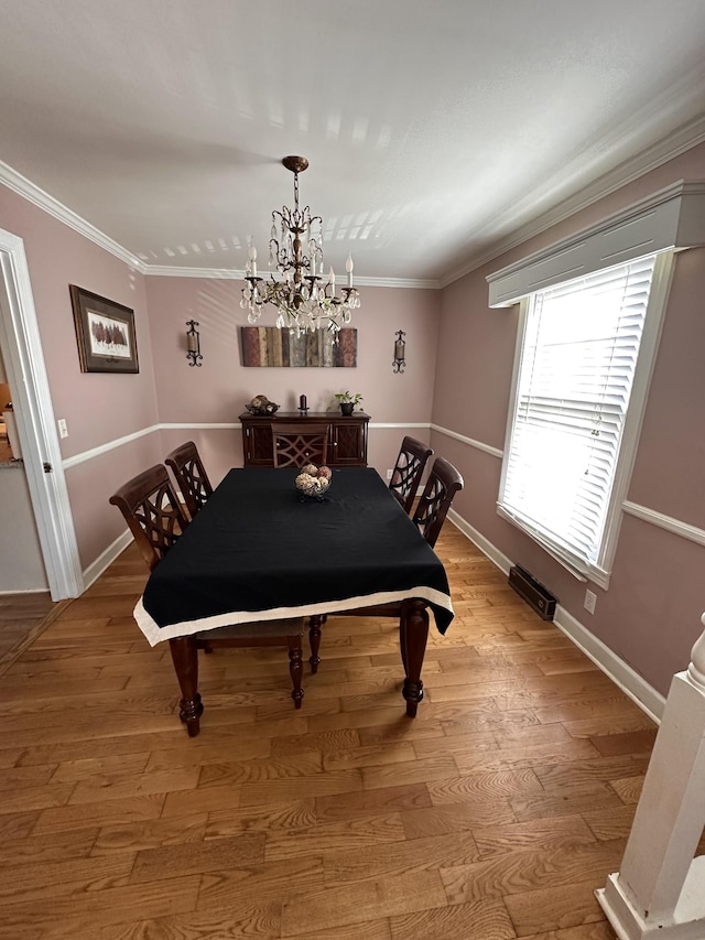 dining room featuring light wood-type flooring, an inviting chandelier, and crown molding