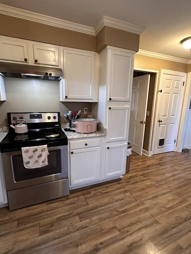 kitchen with hardwood / wood-style floors, white cabinetry, ornamental molding, and stainless steel electric range