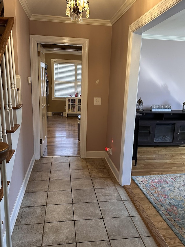 corridor featuring tile patterned floors, ornamental molding, and a chandelier