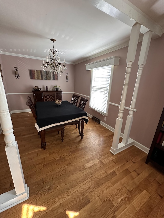 dining room featuring wood-type flooring, a notable chandelier, and crown molding