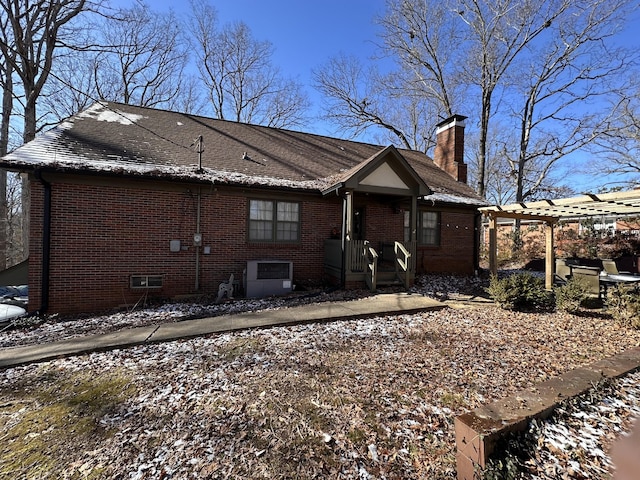 snow covered rear of property featuring a pergola