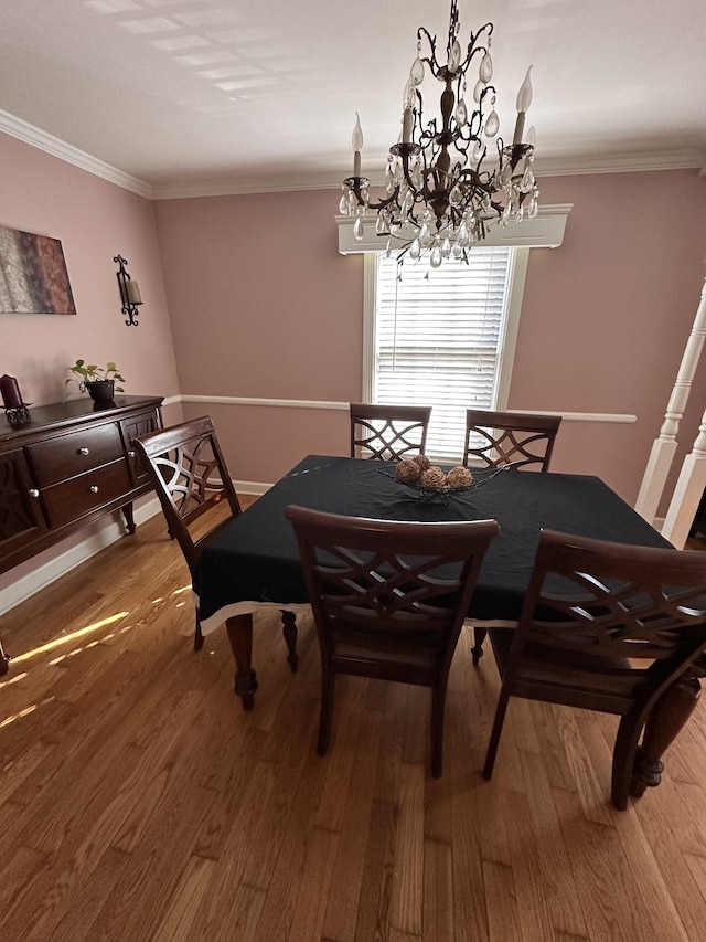 dining space featuring hardwood / wood-style floors, crown molding, and an inviting chandelier