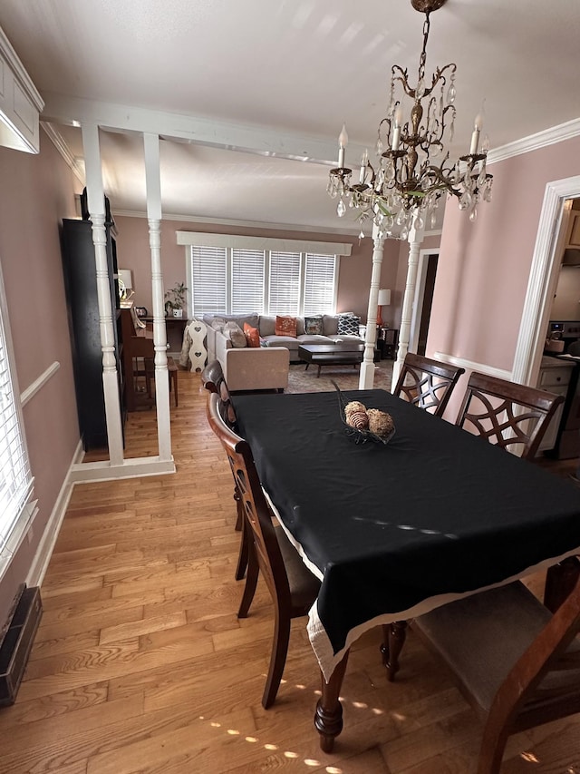 dining area with an inviting chandelier, a healthy amount of sunlight, light wood-type flooring, ornamental molding, and decorative columns