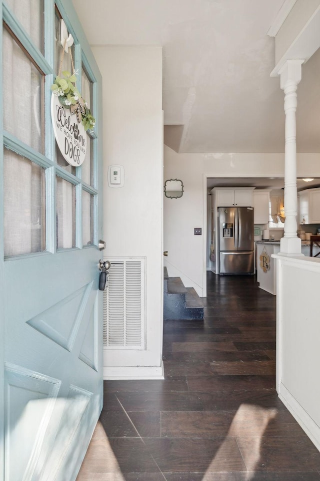 foyer featuring dark wood-type flooring and decorative columns