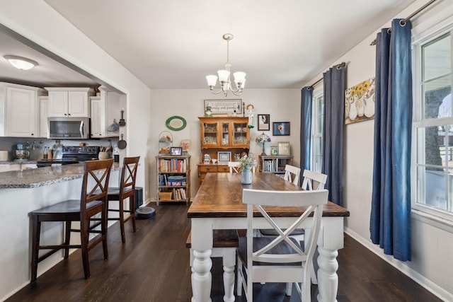 dining space featuring plenty of natural light, dark wood-type flooring, and a notable chandelier