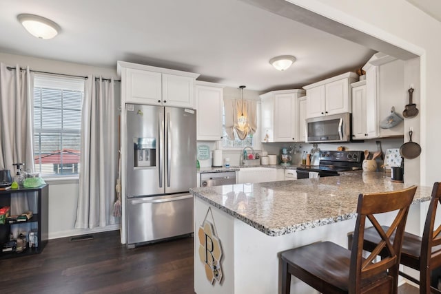 kitchen featuring pendant lighting, white cabinetry, kitchen peninsula, and appliances with stainless steel finishes