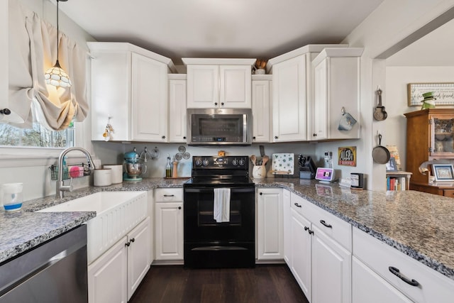 kitchen with stainless steel appliances, white cabinetry, sink, and dark stone counters