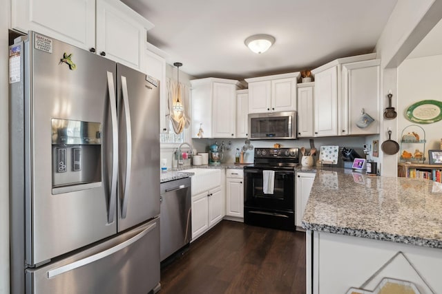 kitchen featuring appliances with stainless steel finishes, decorative light fixtures, sink, white cabinets, and light stone counters