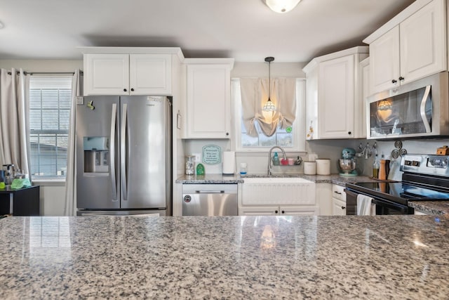 kitchen featuring stainless steel appliances, white cabinets, stone counters, and decorative light fixtures