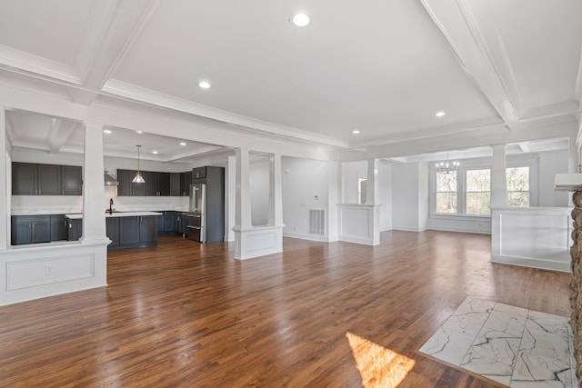 unfurnished living room with sink, dark hardwood / wood-style floors, ornamental molding, and beamed ceiling