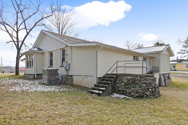 rear view of property with a yard and central air condition unit