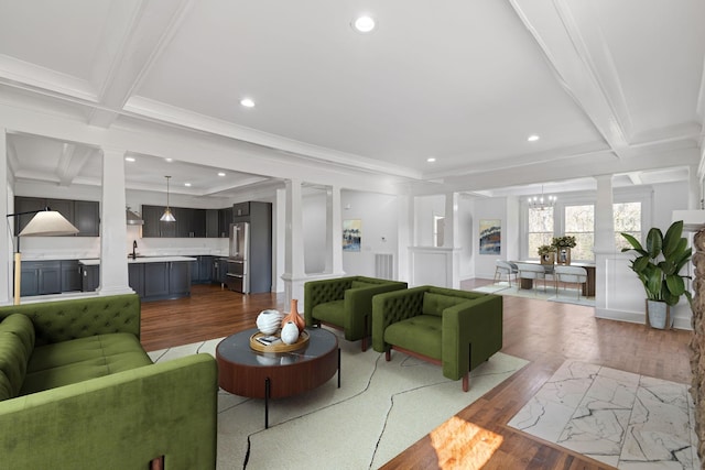 living room with sink, wood-type flooring, crown molding, and beamed ceiling