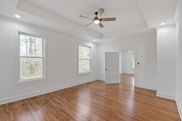 spare room featuring ceiling fan, wood-type flooring, a raised ceiling, and crown molding