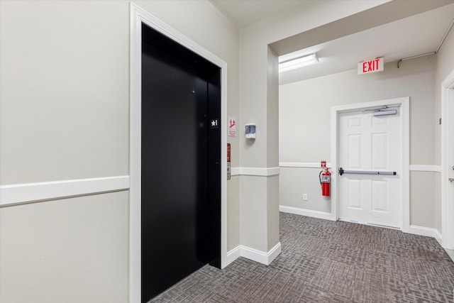 corridor featuring dark carpet and elevator