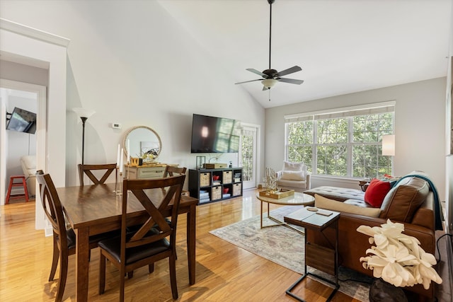 dining room featuring ceiling fan, high vaulted ceiling, and light wood-type flooring