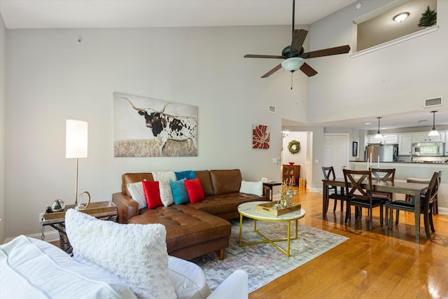 living room with ceiling fan, a high ceiling, and hardwood / wood-style floors