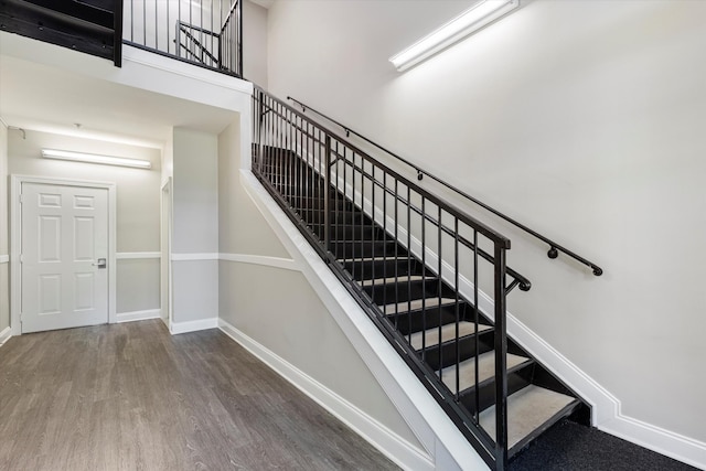 stairs featuring a towering ceiling and hardwood / wood-style flooring