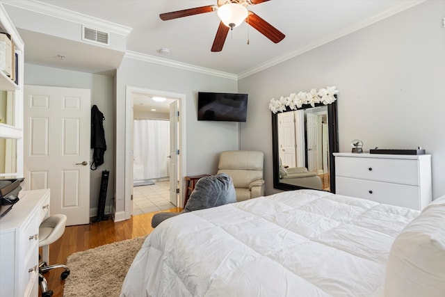 bedroom featuring light wood-type flooring, ceiling fan, crown molding, and ensuite bath