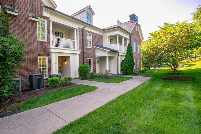 multi unit property with central AC unit, a front yard, and a balcony