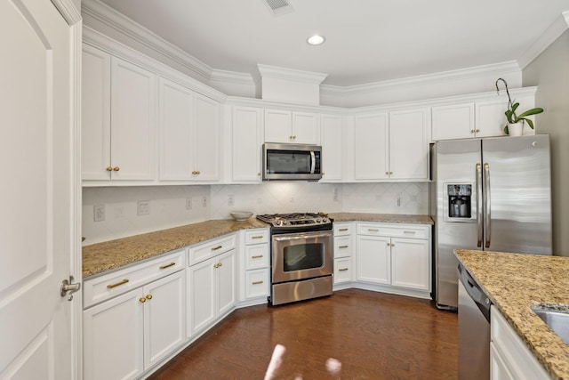 kitchen with appliances with stainless steel finishes, tasteful backsplash, white cabinets, dark hardwood / wood-style flooring, and light stone countertops