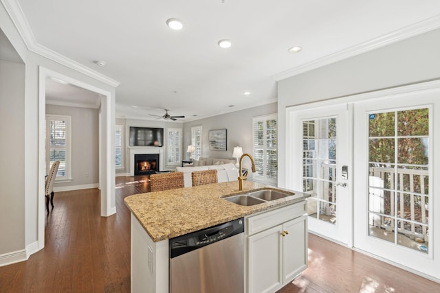 kitchen featuring sink, white cabinets, stainless steel dishwasher, light stone counters, and a center island with sink