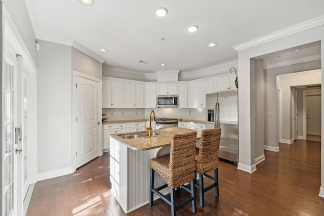 kitchen with white cabinetry, sink, a kitchen island with sink, light stone counters, and stainless steel appliances