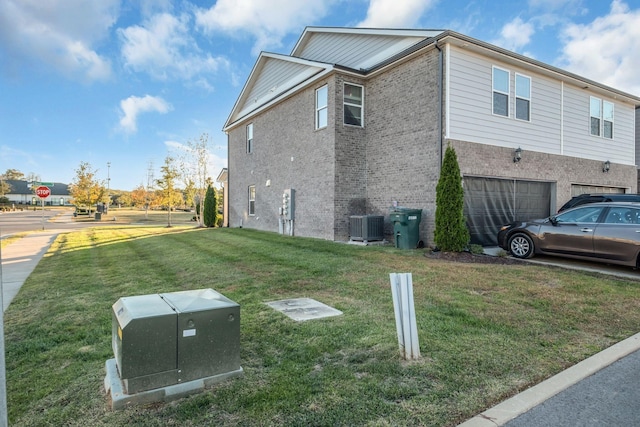 view of side of property with a garage, central air condition unit, and a lawn