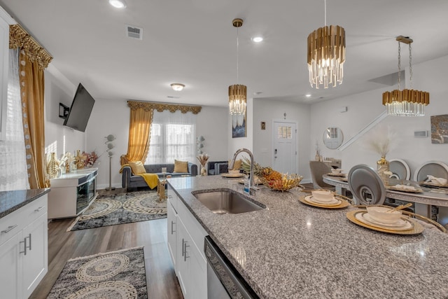 kitchen with decorative light fixtures, white cabinets, sink, and dark stone countertops