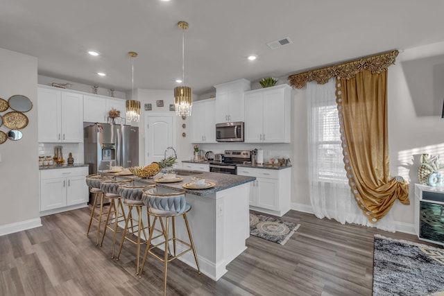 kitchen with appliances with stainless steel finishes, sink, white cabinetry, and hardwood / wood-style floors