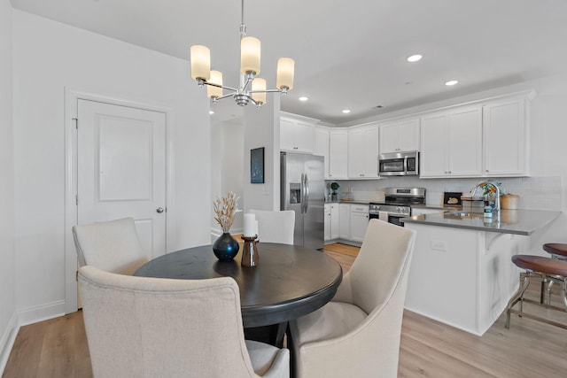 dining room with light wood-type flooring, sink, and an inviting chandelier