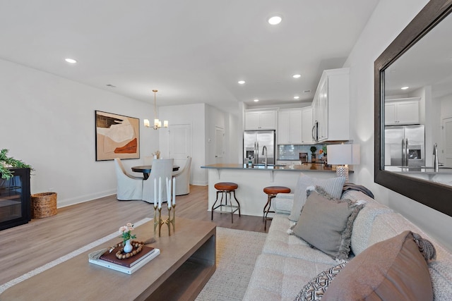 living room with sink, a chandelier, and light hardwood / wood-style flooring