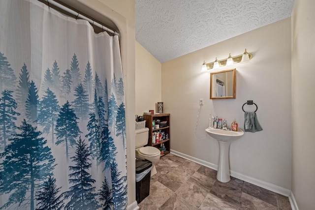 bathroom with a textured ceiling, toilet, and walk in shower