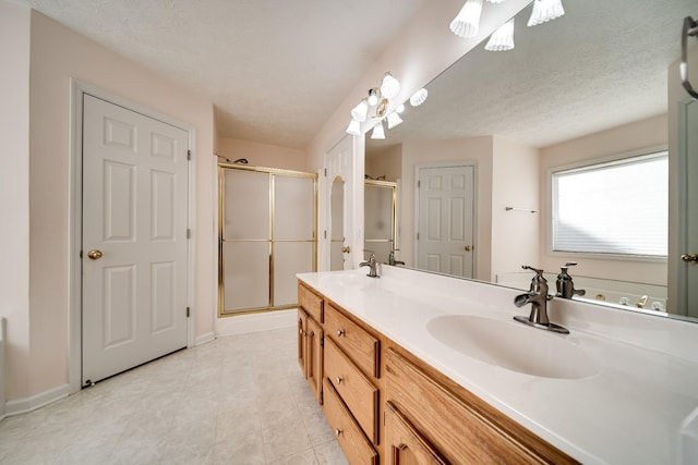 bathroom featuring a shower with shower door, vanity, and a textured ceiling