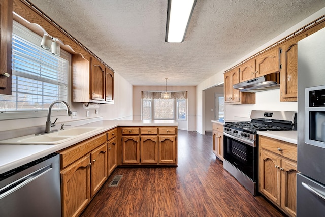 kitchen with pendant lighting, a textured ceiling, stainless steel appliances, sink, and kitchen peninsula