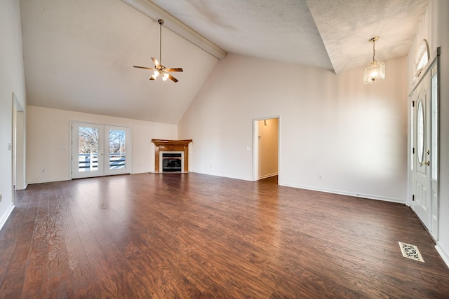 unfurnished living room with dark wood-type flooring, ceiling fan with notable chandelier, high vaulted ceiling, and beamed ceiling