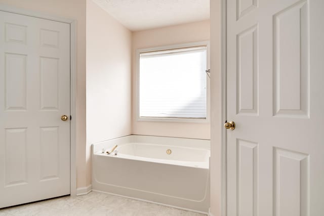 bathroom with a bath, a textured ceiling, and a healthy amount of sunlight