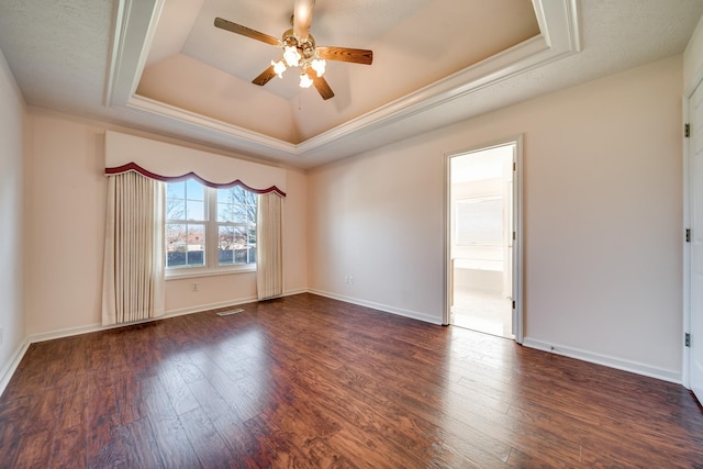 unfurnished room with ceiling fan, dark hardwood / wood-style floors, a tray ceiling, and ornamental molding