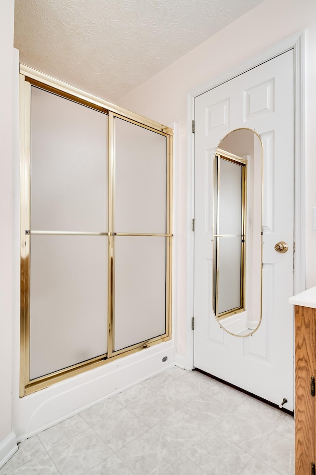 bathroom featuring a shower with shower door and a textured ceiling